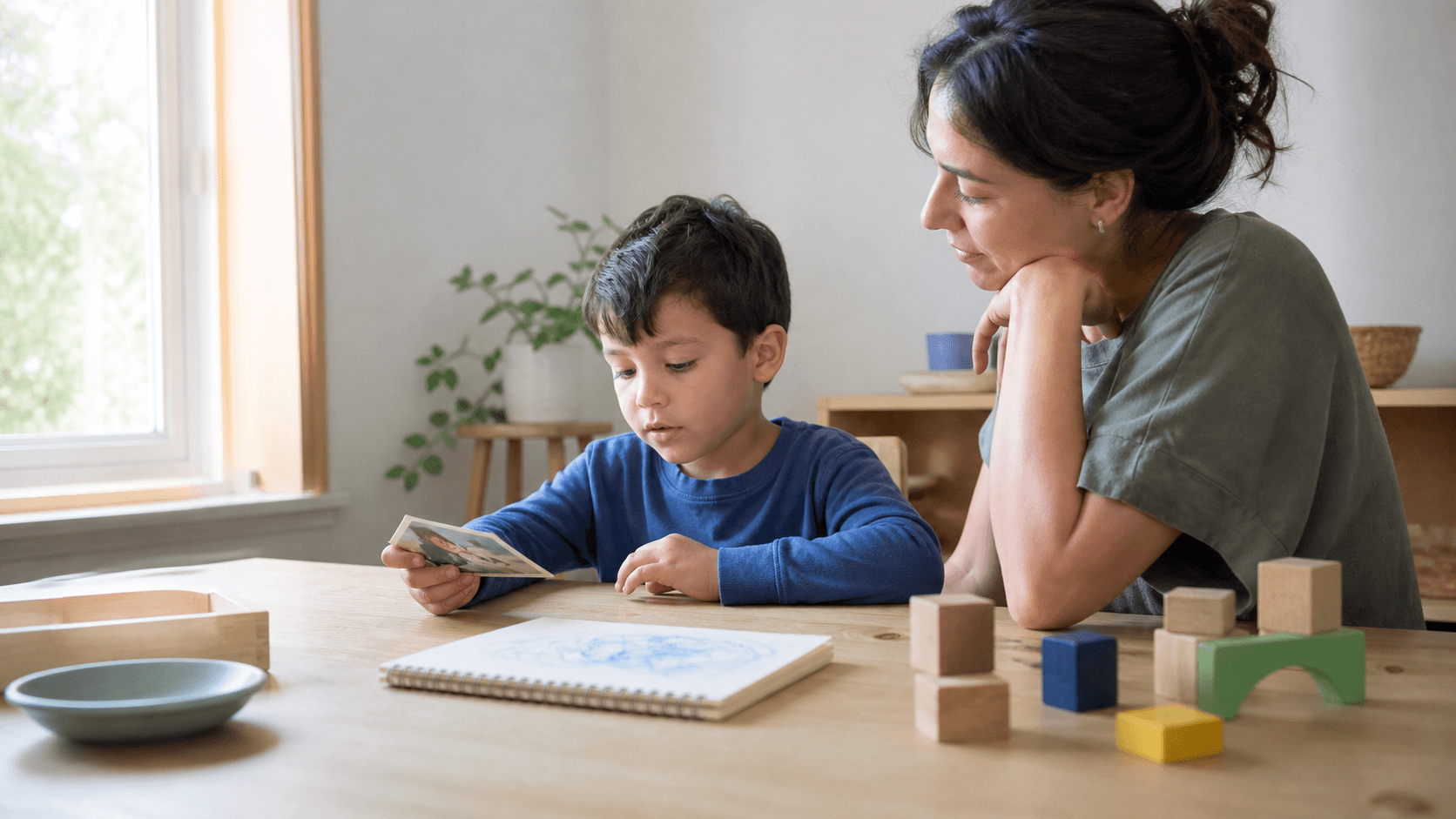 A child choosing a picture card while a supportive adult waits nearby