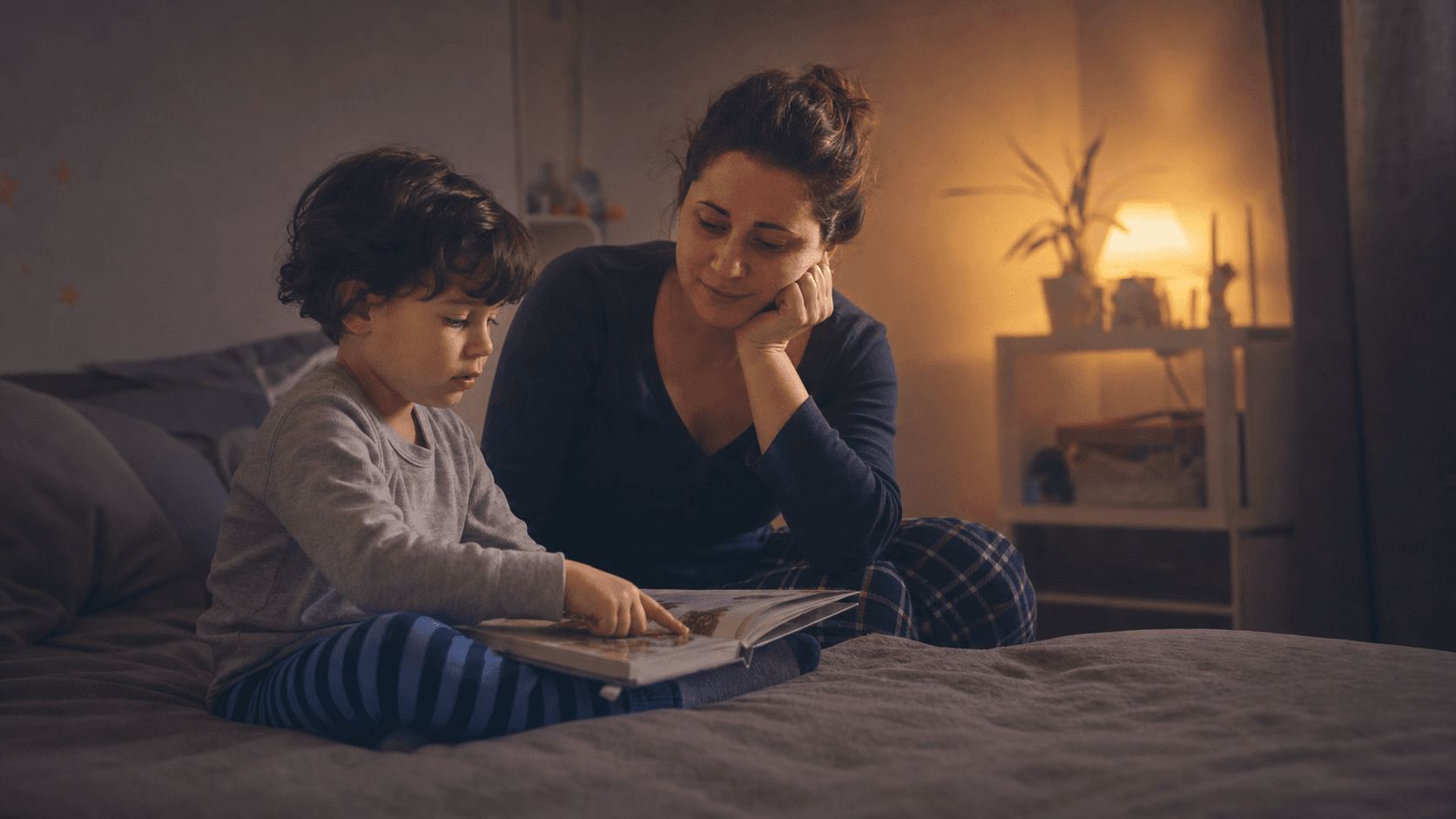 A parent and young autistic child share a quiet bedtime story